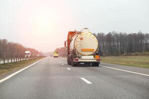 A tanker truck with a semi-trailer transports a dangerous cargo of toxic chemicals along a country road in the spring. Copy space for text photo