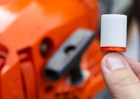 New fuel filter on the background of a chainsaw. The concept of replacing the fuel filter and protecting the engine from impurities, water and dirt in the fuel. photo