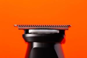 beard trimmer on a red background, close-up. Hair and beard care photo
