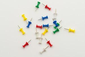 Push pins scattered on a white background in various colors for versatile uses photo