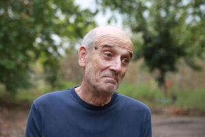 Elderly Man Makes Facial Expression Of We Hope Under A Tree In The Countryside photo