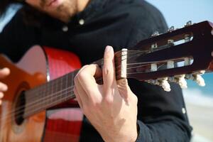 Man Plays Classical Guitar On The Beach Near The Sea In Summer photo