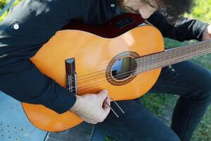 Man Tunes Guitar With Tuning Fork Outside photo