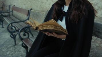 Woman With Cloak Reads The Mysteries In The Book Sitting On A Bench In The City photo