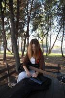 Girl Takes Sheet Music On Table With Bass Instrument In Nature photo