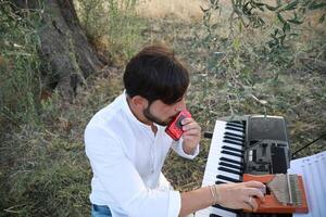 Boy Plays Music With Harmonica And Keyboard Among The Olive Trees Of Calabria photo