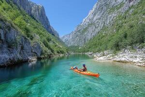 Person kayaking in crystal clear turquoise river amidst towering cliffs under a clear sky. photo