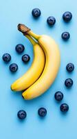 Fresh bananas and blueberries arranged on a vibrant blue background. photo