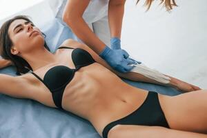 Putting cream on the hands., Woman is having sugaring procedure in the clinic by female doctor photo