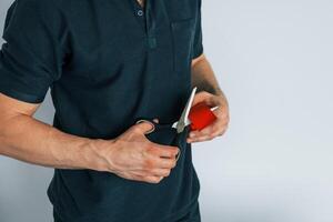 Using scissors to cut the product. Professional physiotherapist is standing indoors with kinesio tape, photo