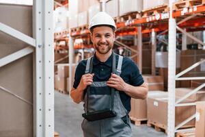 Smiling for the camera. Employee in uniform is working in the storage at daytime,, photo