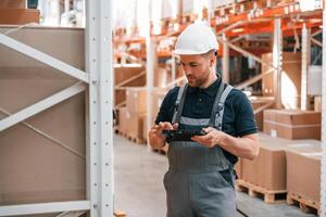 Checking data. Employee in uniform is working in the storage at daytime photo