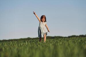 Enjoying nature. Happy girl have a walk outdoors on the field at summer photo
