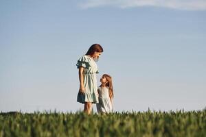 Holding each other by hands. Mother and daughter have fun outdoors on the field at summer photo