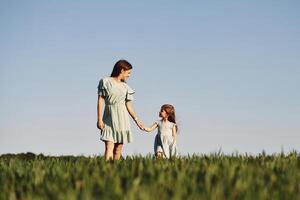Holding each other by hands.. Mother and daughter have fun outdoors on the field at summer photo