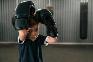 Portrait of boy that is practicing boxing in the gym with glowes on hands, photo