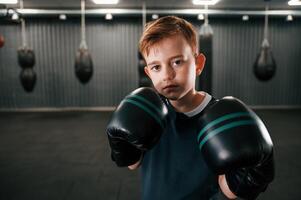 Portrait of boy that is practicing boxing in the gym with glowes on hands photo