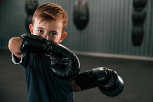 Portrait of boy that is practicing boxing in the gym with glowes on hands. photo
