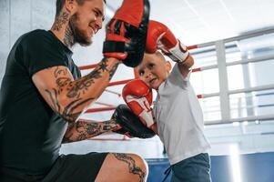 How to punch correct way,. Coach is teaching the boy box techniques indoors photo