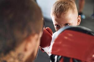 How to punch correct way. Coach is teaching the boy box techniques indoors photo