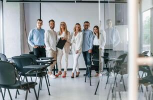 Standing and posing for a camera in the class.. Group of professional business people is in the office photo