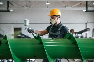 Painting details. Man in uniform is in workstation developing details of agriculture technique. photo