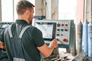Standing near operate device. Man in uniform is in workstation developing details of agriculture technique, photo