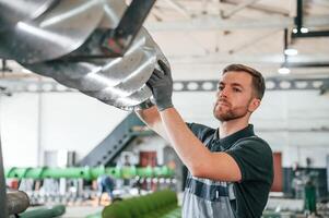 Checking slicing parts. Man in uniform is in workstation developing details of agriculture technique photo