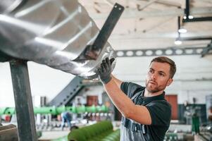 Checking slicing parts.,. Man in uniform is in workstation developing details of agriculture technique photo