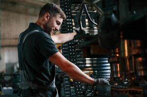 Metal processing device. Man in uniform is in workstation developing details of agriculture technique., photo