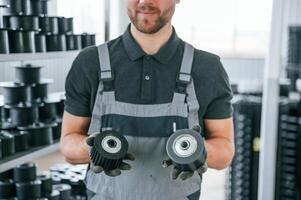 Holding replaceble parts. Man in uniform is in workstation developing details of agriculture technique photo
