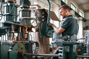 Metal processing device. Man in uniform is in workstation developing details of agriculture technique. photo