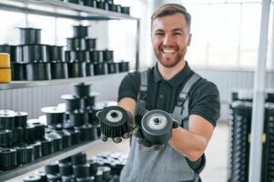 Holding objects and smiling. Man in uniform is in workstation developing details of agriculture technique. photo