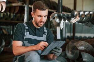 Manager is using digital tablet. Man in uniform is in workstation developing details of agriculture technique photo