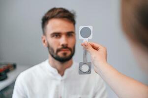 Holding tool. ,Man's vision checked by female doctor in the clinic by using special optometrist device photo