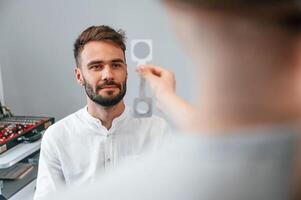 Holding tool. Man's vision checked by female doctor in the clinic by using special optometrist device photo