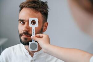 Holding tool.. Man's vision checked by female doctor in the clinic by using special optometrist device photo