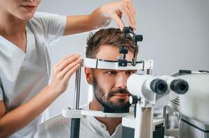 Man's vision ,checked by female doctor in the clinic by using special optometrist device photo
