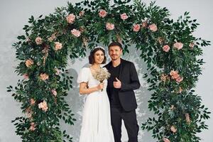 Standing against flowers. ,Beautiful bride with his fiance is on the wedding photo