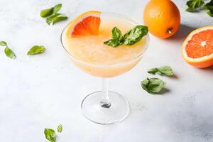 An orange and mint cocktail with a garnish photo