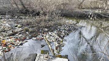 Dirty river is polluted with many plastic bottles. A lot of trash is dumped in open and freely available places at nature. Global environmental pollution problem. Concept of ecological disaster photo