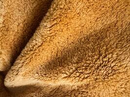 Soft golden fabric close-up reveals intricate textures and patterns in bright light photo