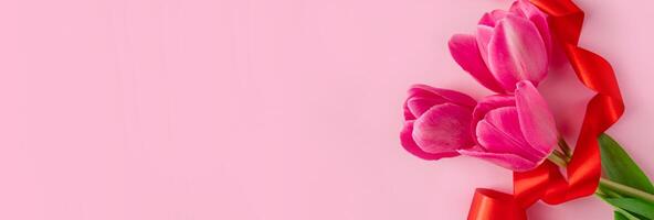 Bouquet of colorful fresh tulips with red ribbon on pink background. Symbol of spring. Happy easter photo