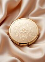 golden compact powder with floral pattern on satin background, closeup. Vintage Gold Compact Mirror photo