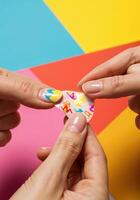 Female hands holding a colored heart on a colorful background, closeup. Applying Nail Art Stickers photo