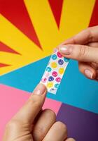 Close-up of a woman hand holding a nail mask with colorful dots on pop art background. Colorful Dotted Washi Nail Mask photo