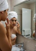 Boys applying skincare routine in front of mirror in bathroom with towel.Young boys Skincare Routine photo