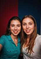 Portrait of two young women in front of a red and blue background. Twin Sisters Selfie photo