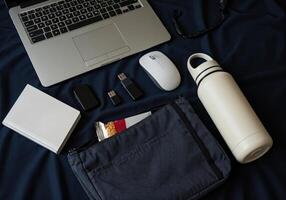 Flat lay composition with laptop, mobile phone, notebook and other objects on black fabric. Work essentials photo