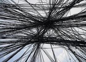 Abstract background of tangled wires and blue sky with white clouds in the background. Tangled City Cables photo